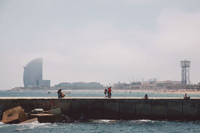 People standing by sea against sky