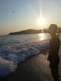 Man standing on beach against sky during sunset