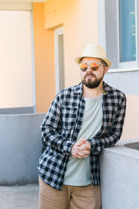 Portrait of young man standing against wall