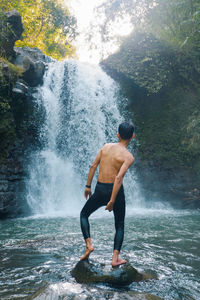 Man surfing on rock in sea