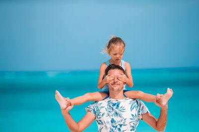 Low angle view of smiling boy against sea against sky