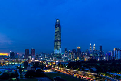 Illuminated buildings against blue sky at night