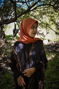 Mid adult woman standing against trees