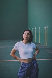 Portrait of young woman standing against wall