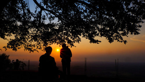 Silhouette man by tree against sky during sunset