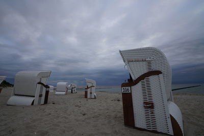 Hooded chairs on beach against sky
