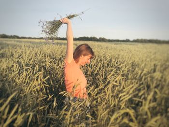 Girl in wheat field against clear sky