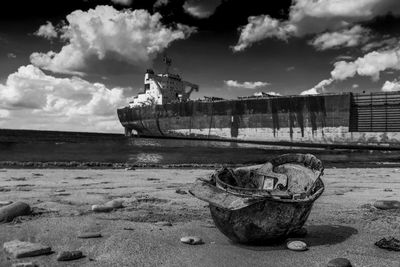 Abandoned helmet at beach against shipwreck in sea