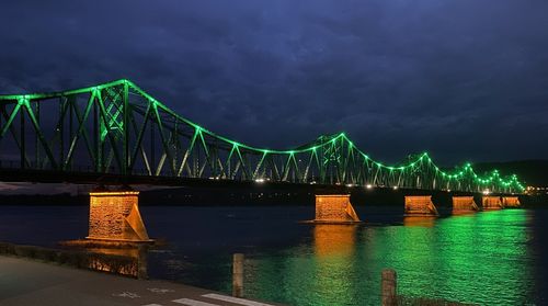 Illuminated bridge over river against sky at night