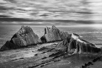 Rock formations by sea against sky