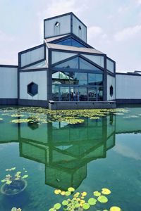 Reflection of building on swimming pool against sky