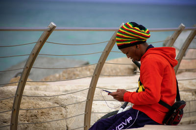 Side view of a man sitting on railing