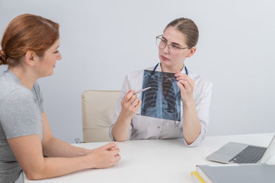 Young woman using laptop while sitting on bed at home