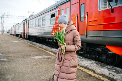 Girl with a bag and flowers on the platform of the station