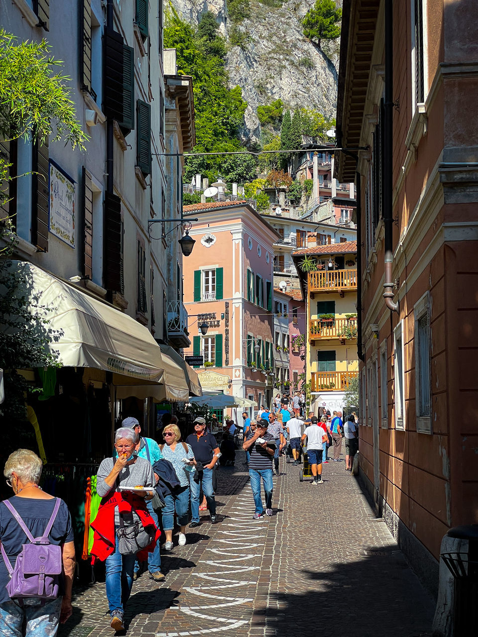 GROUP OF PEOPLE WALKING ON STREET AMIDST BUILDINGS