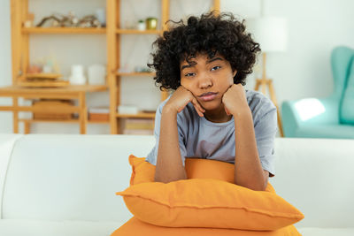 Portrait of young woman sitting on sofa at home