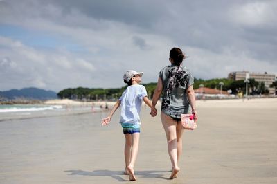 Rear view of women on beach against sky