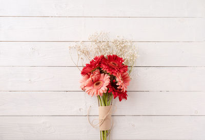 Red gerbera daisy flowers on white wooden table