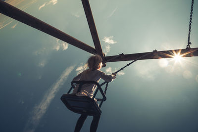 Low angle view of girl enjoying swing against sky