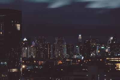 Illuminated cityscape against sky at night