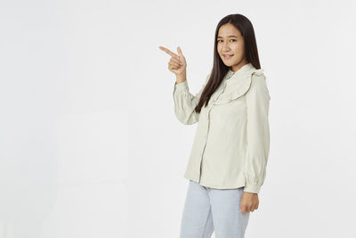Portrait of smiling young woman standing against white background