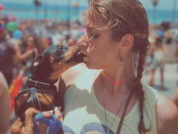 Woman kissing dachshund during sunny day