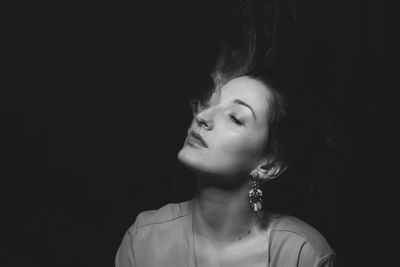 Close-up of thoughtful woman with eyes closed against black background