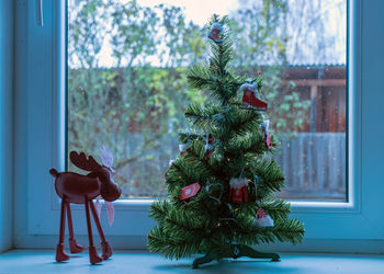 Decorated christmas tree on windowsill, window view, christmas decor, winter