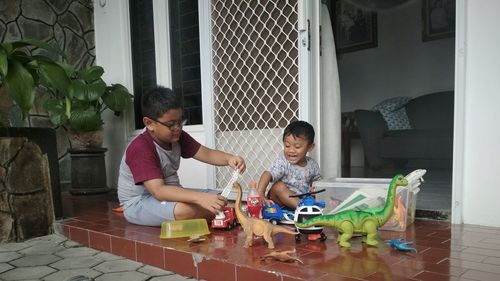 Siblings playing with toys at porch