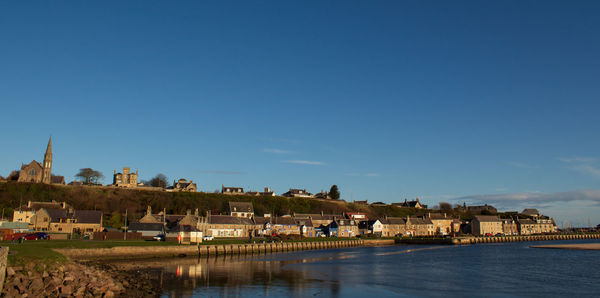 Houses by river against sky in town
