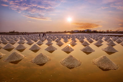 Salt farm against cloudy sky during sunset