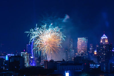 Firework display over illuminated buildings in city at night