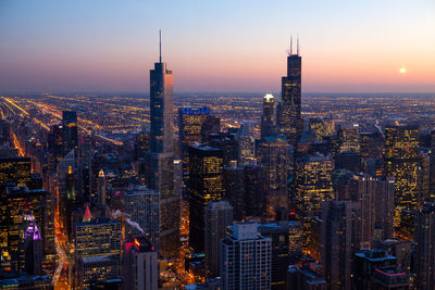 Aerial view of illuminated city buildings during sunset