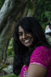 Portrait of smiling young woman sitting at park