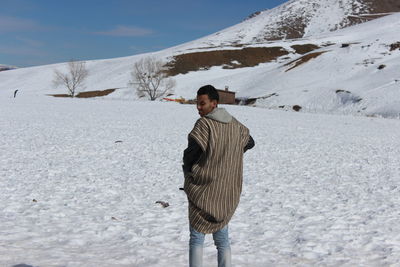 Rear view of man standing on snow covered land