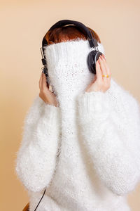 Portrait of person hiding behind face against wall