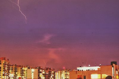 Illuminated buildings against sky at sunset