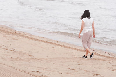 Rear view of woman walking on beach