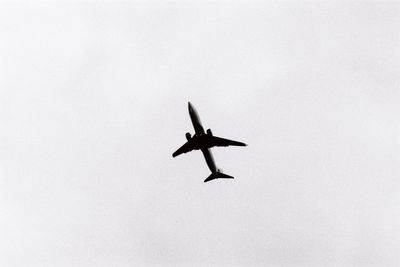 Low angle view of silhouette airplane against clear sky
