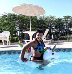 Side view portrait of smiling young woman in swimming pool