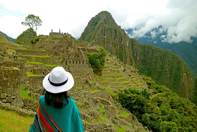 Rear view of woman looking at mountains against sky