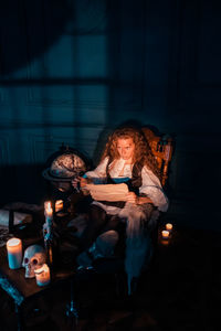 Young woman sitting in illuminated room