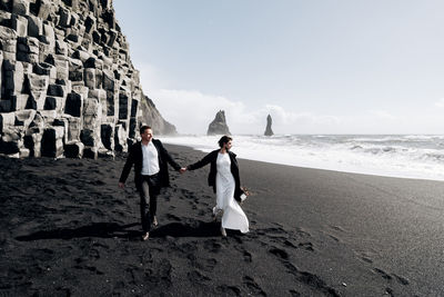 People walking on beach by sea against sky