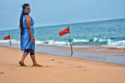 Woman standing on beach against sky