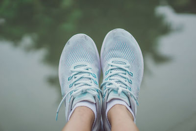 Low section of woman wearing shoes against lake