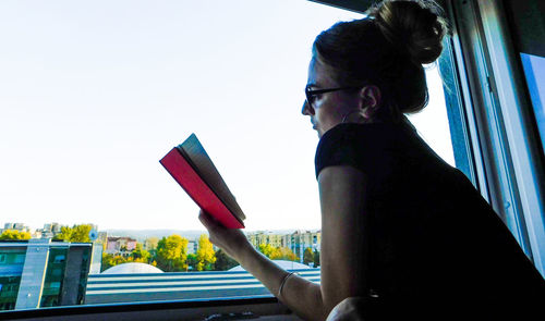 Side view of woman using mobile phone against sky