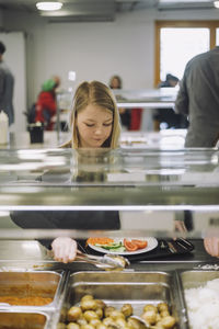 Girl taking food from food bar during lunch break in cafeteria