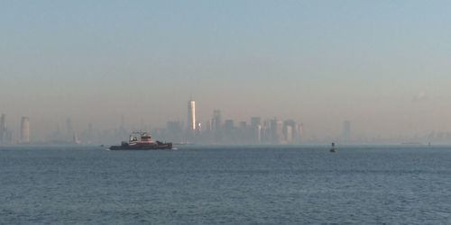 Sailboats in sea against buildings in city