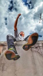 Silhouette of young boy against cloudy sky with a smartphone 