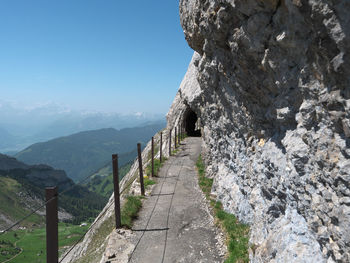 Footpath leading towards mountains against clear sky